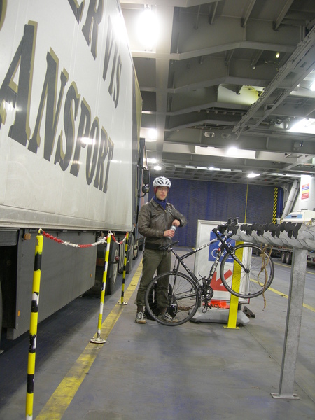 Ik bind de fiets vast met een gevonden veter aan het rek. Er is verderop nog een fietsenrek, ik ben niet de enige. Verder staan er 300 vrachtwagens en 200 personenauto's op 6 dekken.